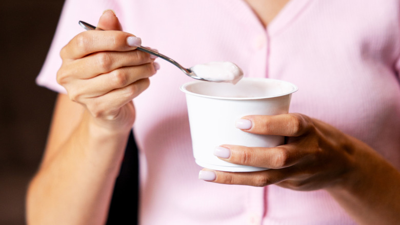 person eating container of yogurt