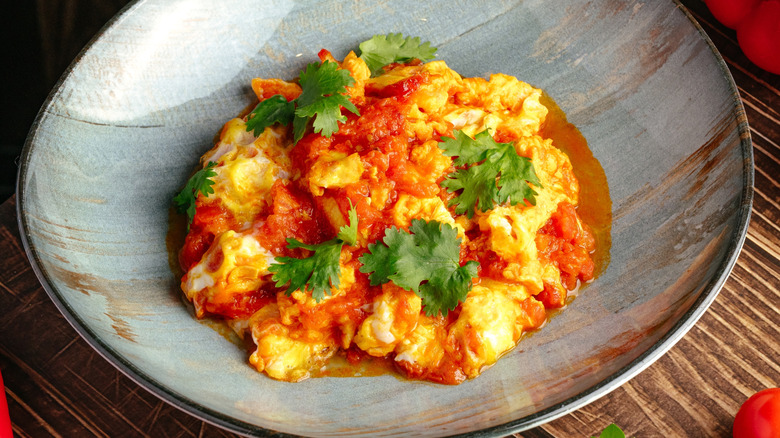 A bowl of Mexican-style scrambled eggs with tomatoes, cheese, and cilantro