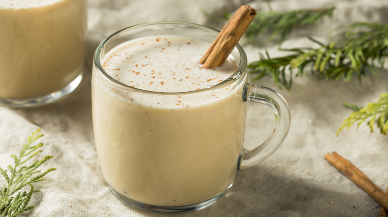 A glass of coquito with cinnamon sticks
