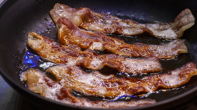 Strips of bacon frying in grease