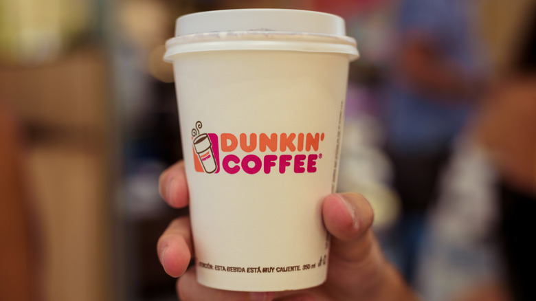 Someone holding a Dunkin coffee cup