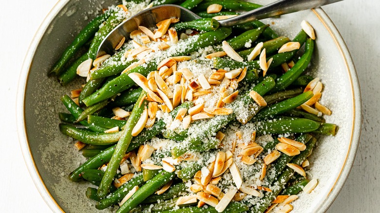 Top-down view of a bowl of green bean almondine with Parmesan