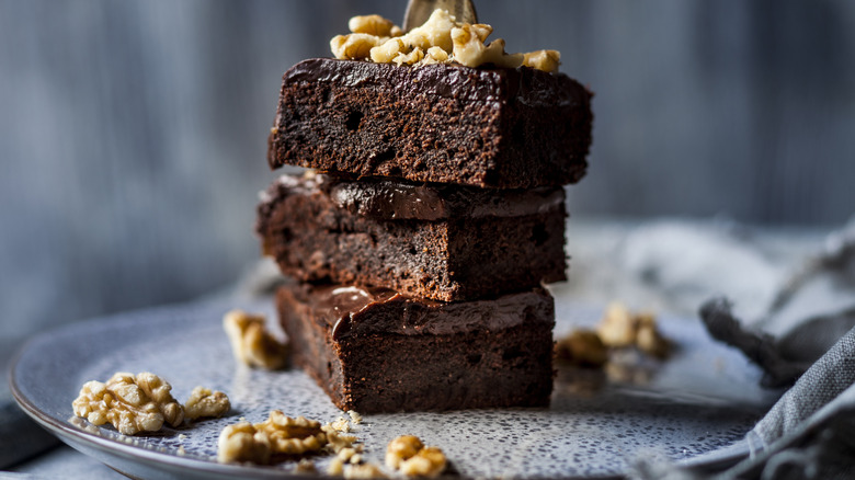 Stack chocolate brownies with walnuts, fork, rustic plate