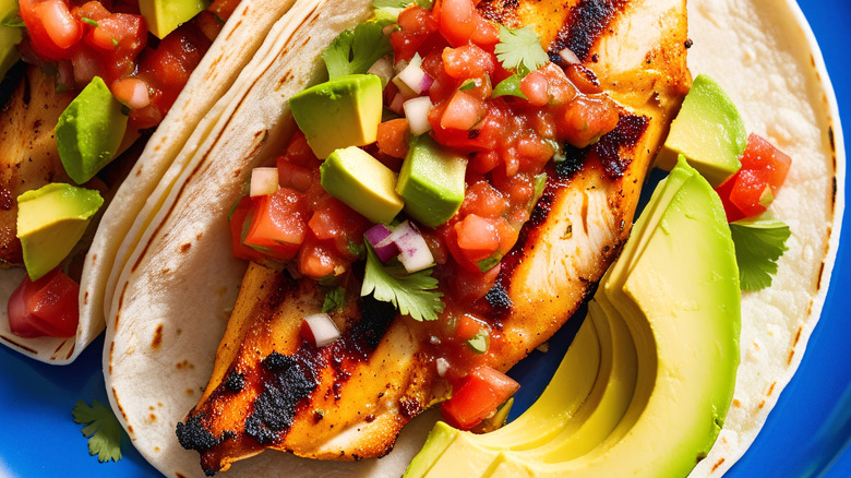 A grilled chicken taco with salsa and avocado