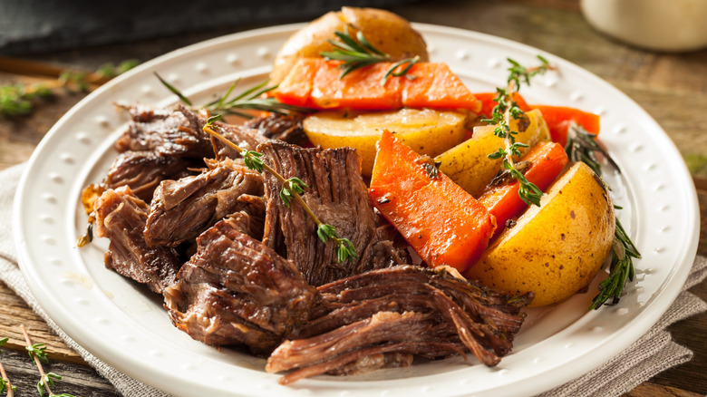 white plate of pot roast with carrots and vegetables