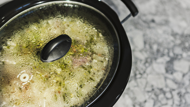 A slow cooker with a lid in place, the glass distorted by the amount of condensation on it