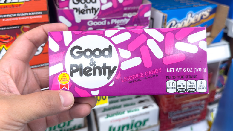 Hand holding up a pink package of Good & Plenty candy
