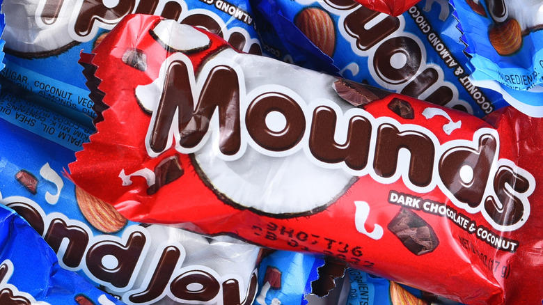 Red Mounds chocolate bar pictured with several blue Almond Joy bars in the background.