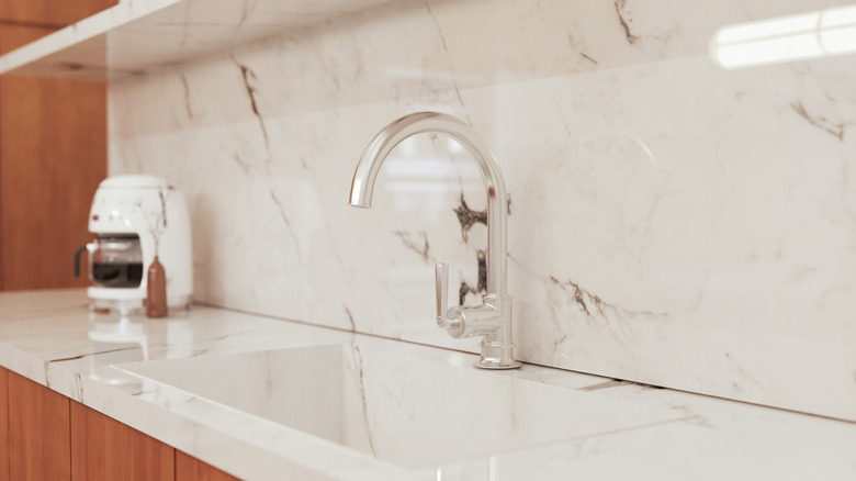 Close0up of kitchen sink with white marble on the backsplash
