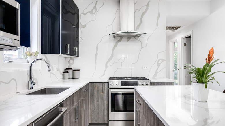 A modern kitchen with marble-effect walls and white countertops