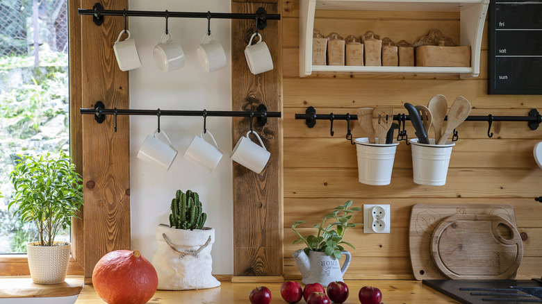 A view of a Tuscan-style kitchen with wood paneling on the backsplash, vintage rods, and rustic decor