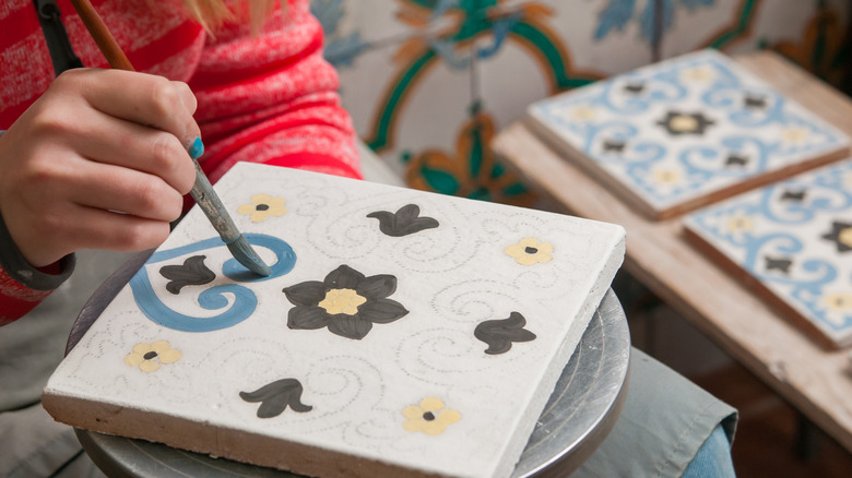 A pottery decorator painting tiles by hand