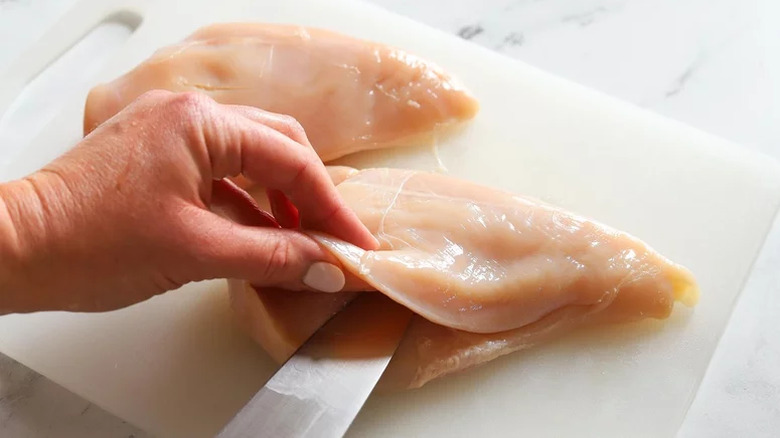 Slicing chicken breast open with a knife
