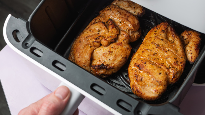 Person cooking chicken breasts in air fryer