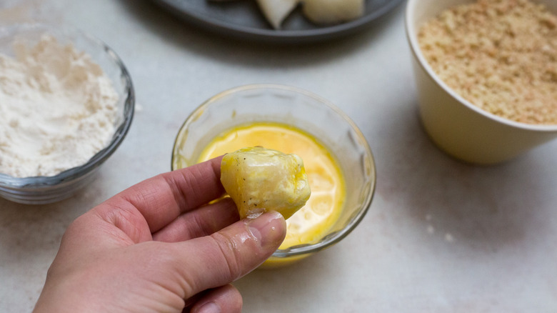 hand holding egg-dipped fish