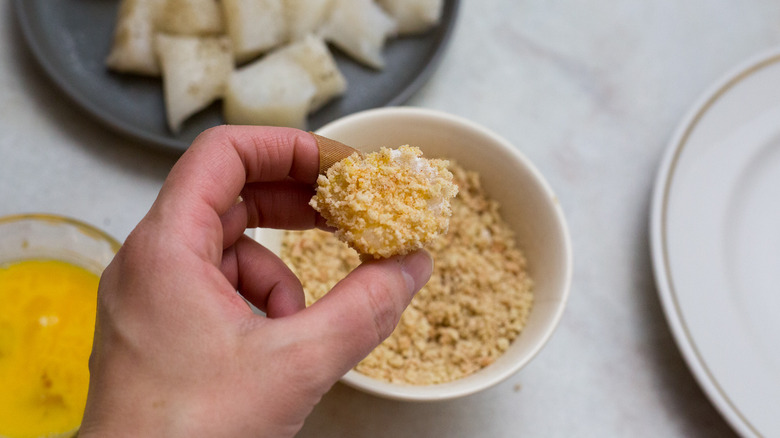 hand holding breadcrumb-coated fish nugget