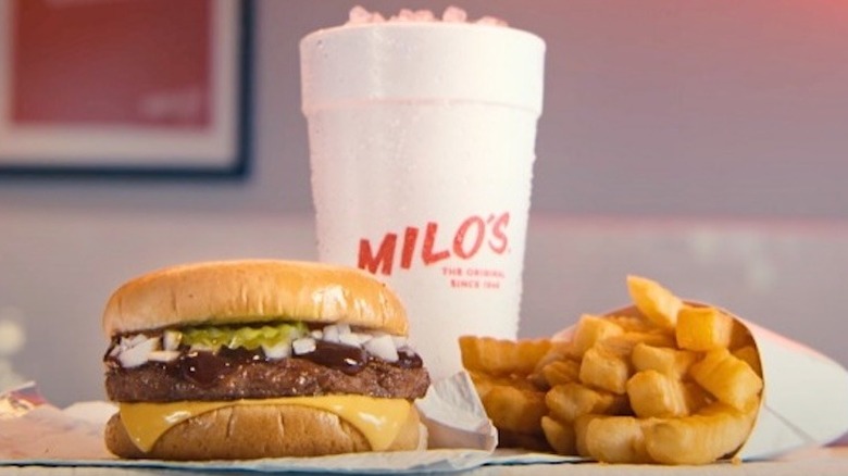 Milo's hamburger and fries beside a styrofoam cup