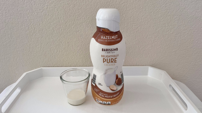 Aldi's Barissimo Delightfully Pure Hazelnut Coffee Creamer in a glass next to its container