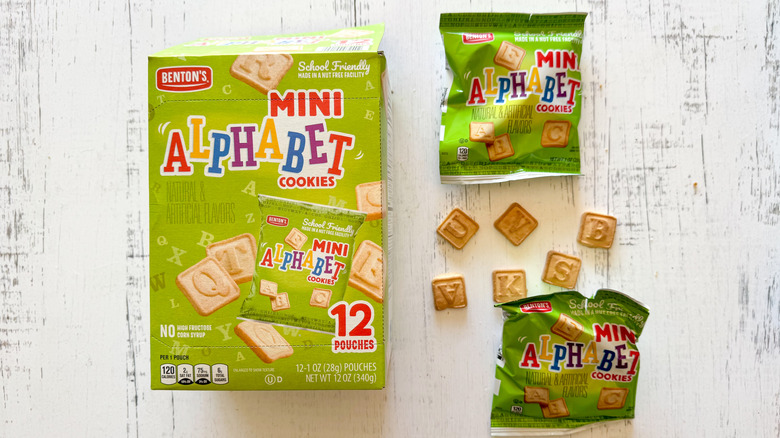 Benton's mini alphabet cookies and packages on a white wooden surface