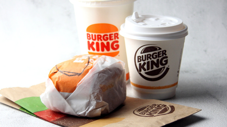 A Burger King coffee cup with a sandwich and a bag
