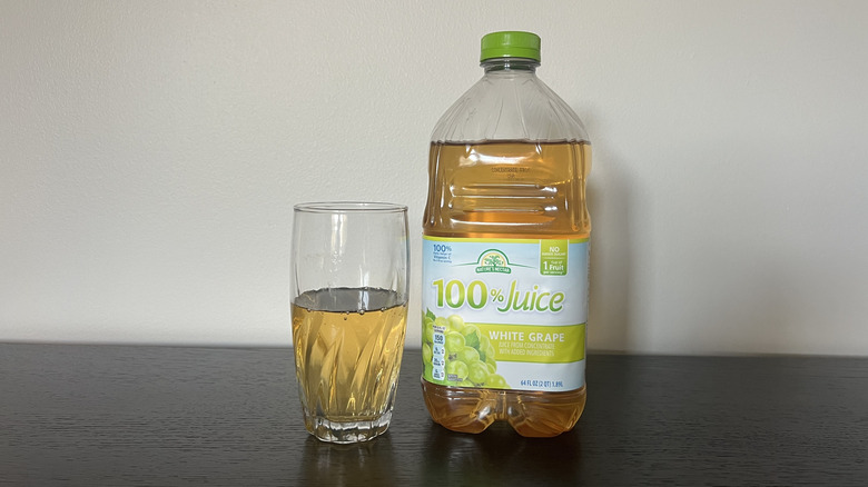 Nature's Nectar white grape 100% juice in a glass next to the bottle