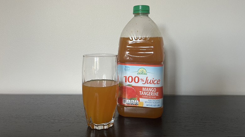 Nature's Nectar mango tangerine 100% juice in a glass next to the bottle