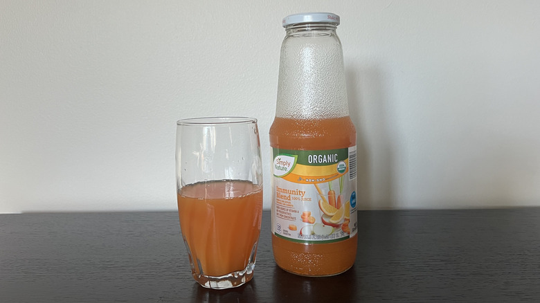 Simply Nature immunity blend 100% juice in a glass next to the bottle