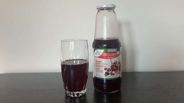 Simply Nature organic super food 100% juice in a glass next to the bottle