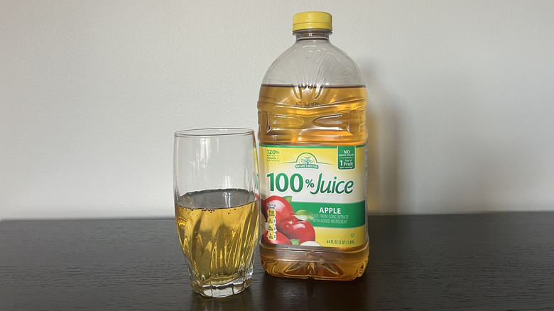 Nature's Nectar apple 100% juice in a glass next to the bottle