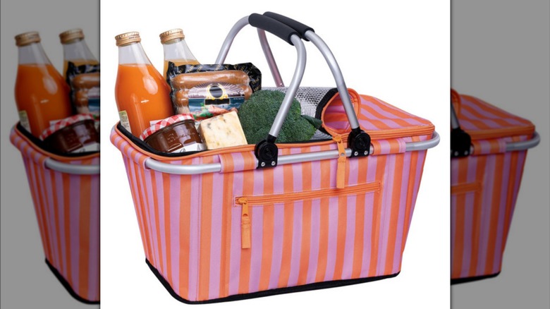 Stock image of a pink and orange striped soft-sided cooler holding drinks, sausages, cheese, jam, and broccoli
