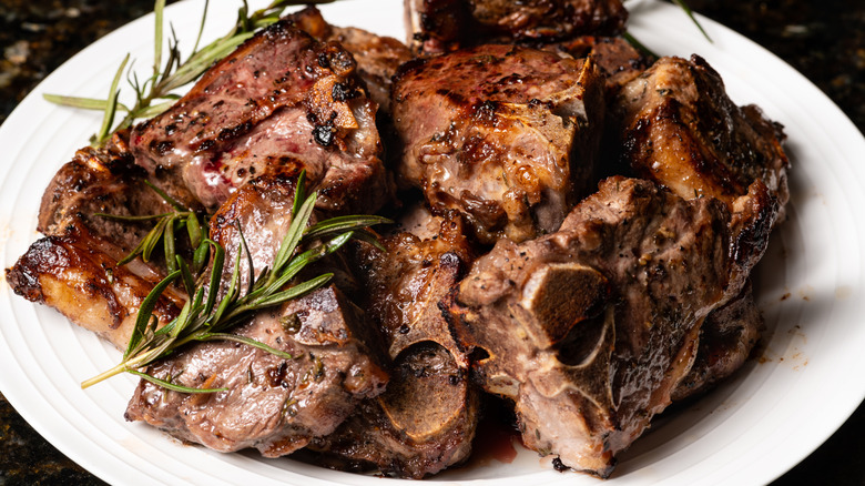 grilled lamb loin chops on a white plate with rosemary
