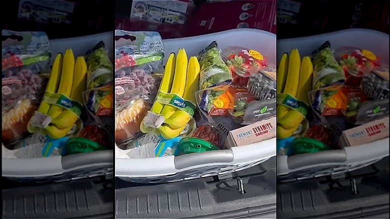 A laundry basket full of groceries in the back of a car
