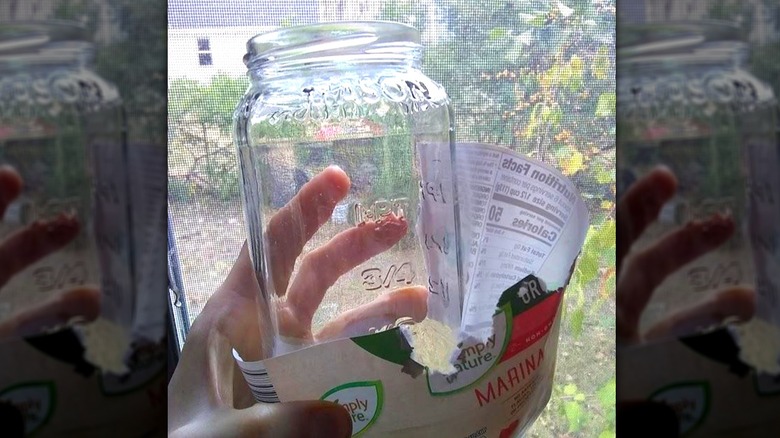 person holding cleaned Aldi Simply Nature Organic Marinara Pasta Sauce jar with label off