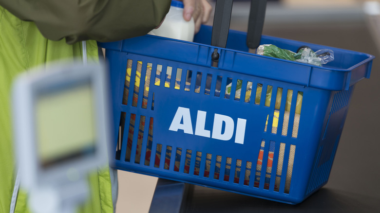 Man holding Aldi basket with food items inside