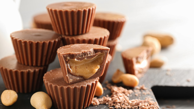 Close-up shot of peanut butter cups stacked on top of each other with peanut butter oozing from one halved cup.