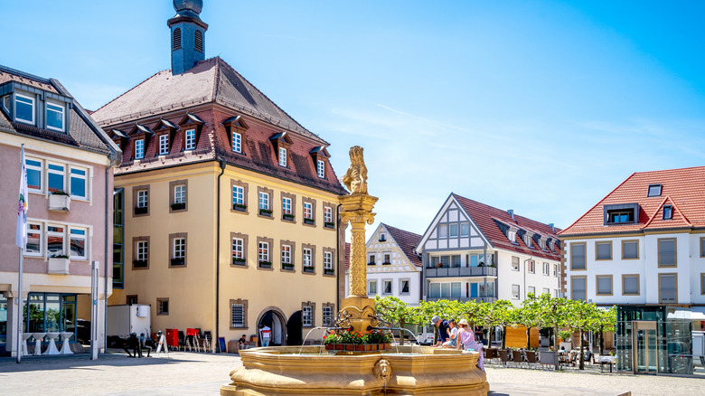 A square in Neckarsulm, Germany with a gold fountain and traditional architecture