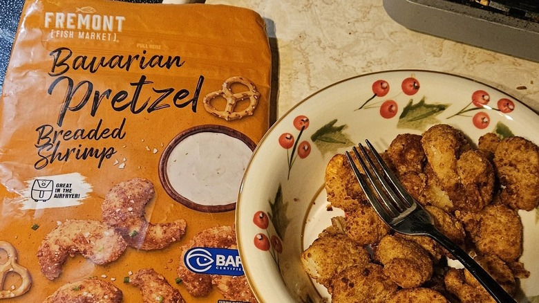 A bag of Fremont Bavarian Pretzel Breaded Shrimp next to a bowl of the shrimp with a fork resting on top