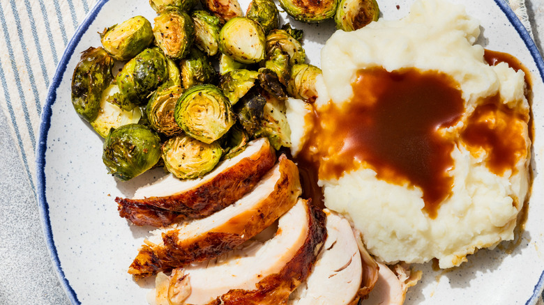 A Thanksgiving plate of turkey, mashed potatoes, gravy, and Brussel sprouts
