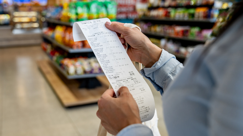 A person looks at their receipt in a grocery store after checking out