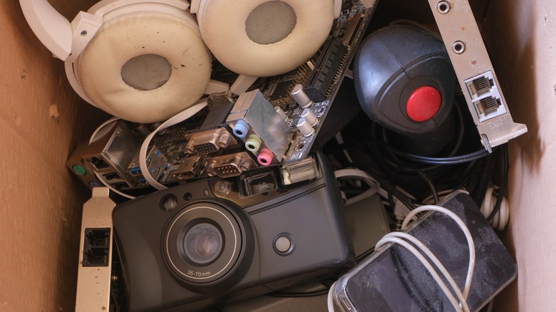 A box of jumbled electronics, including headphones and cords