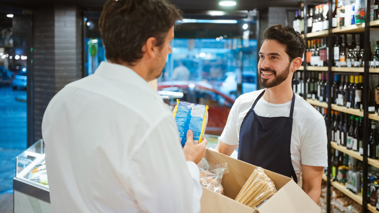 A man discusses a box of food to a smiling cashier