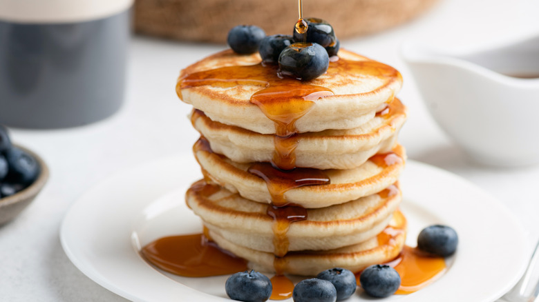 A stack of vegan pancakes with blueberries and maple syrup