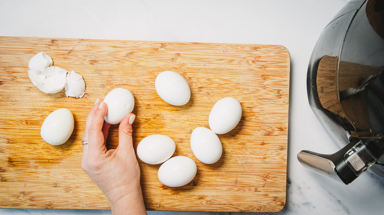 Peeling eggs on cutting board.