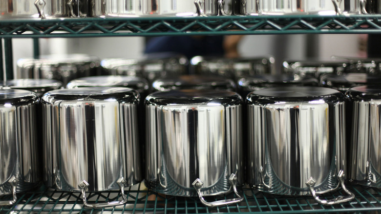 All-Clad stainless steel cookware lined up on a shelf