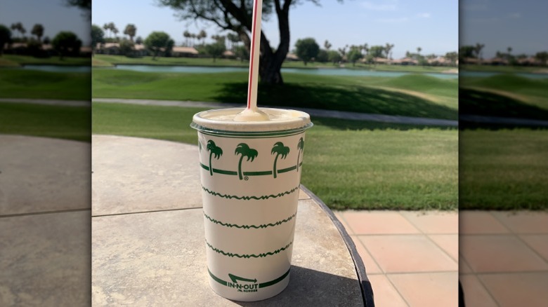 An In-N-Out milkshake on an outdoor table.