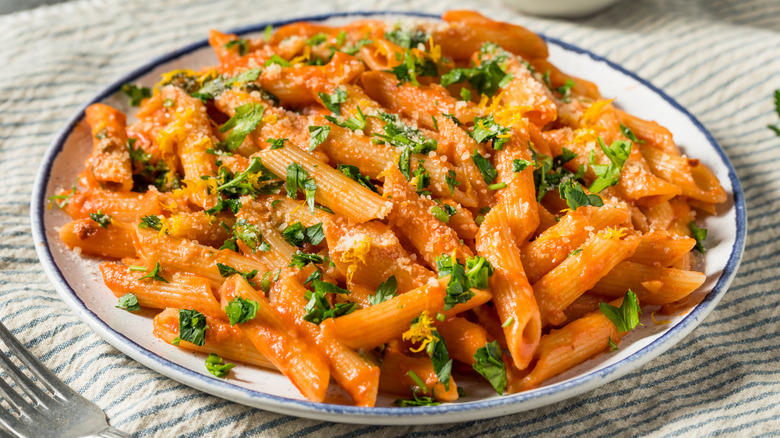 a large plate of penne alla vodka with parsley on top