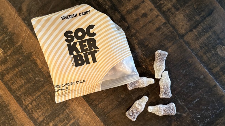 Sockerbit sour cherry cola gummies in bag and on wooden background.
