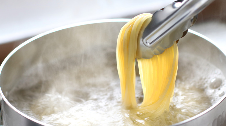Removing spaghetti from water with tongs