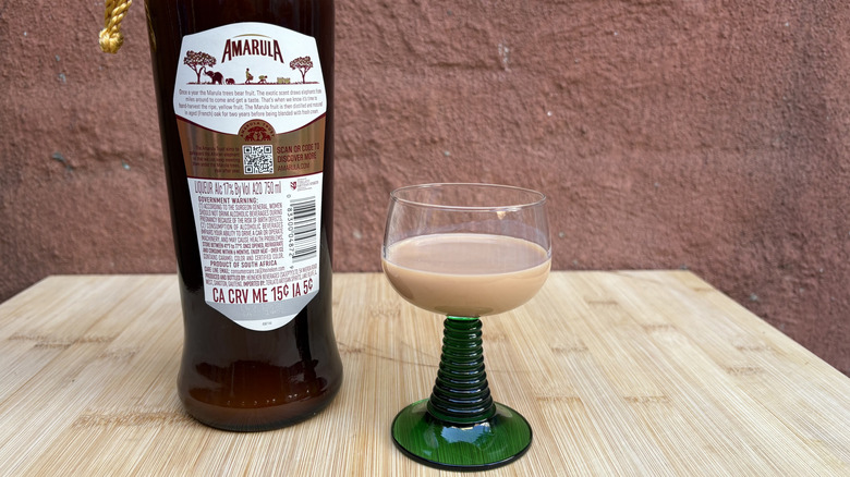 Bottle of Amarula and glass with red background