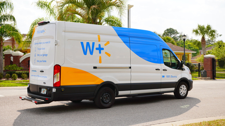 A white blue and yellow Walmart Plus delivery truck parked in a neighborhood